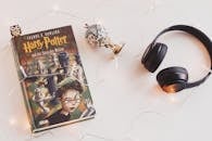 Minimalist setup with Harry Potter book, headphones, and string lights for a cozy reading experience.